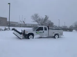 Commercial snow plow truck clearing a parking lot in Kansas City
